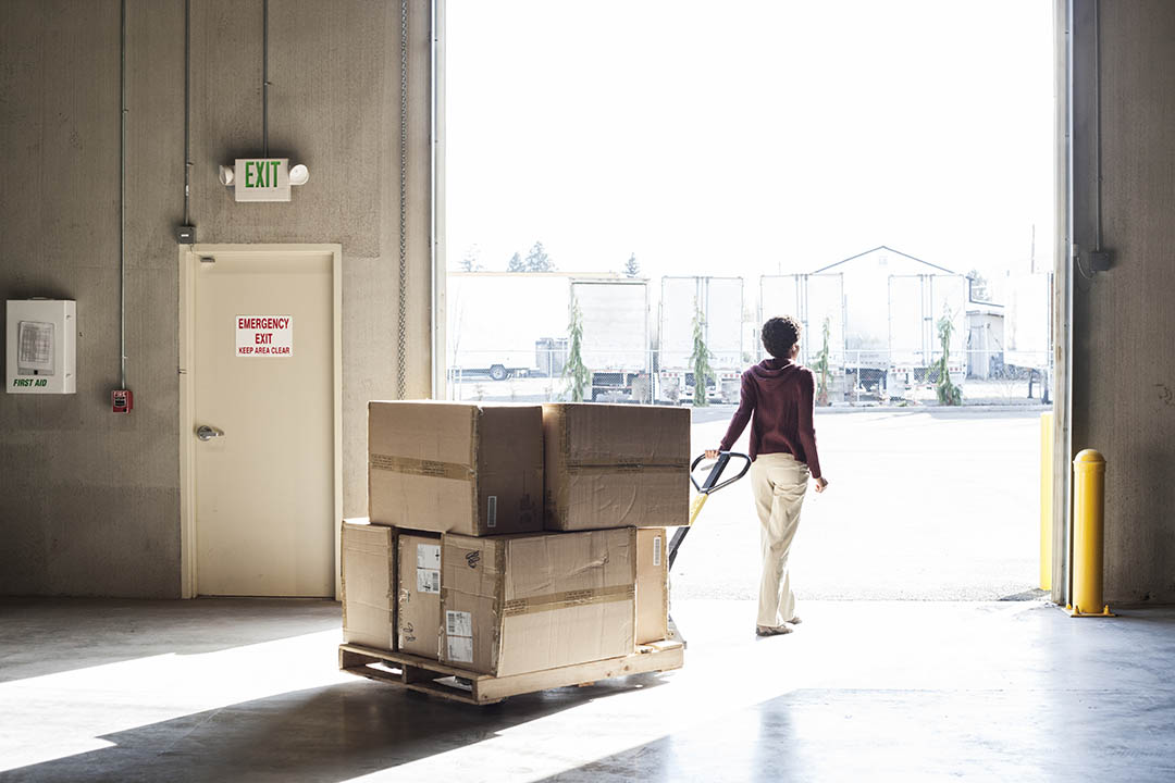 a-female-warehouse-worker-moving-products-with-a-p-XJ8UMNJ.jpg